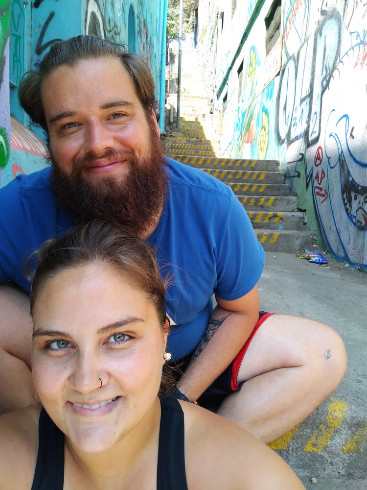 Eu e a Ju em uma escadaria com paredes grafitadas